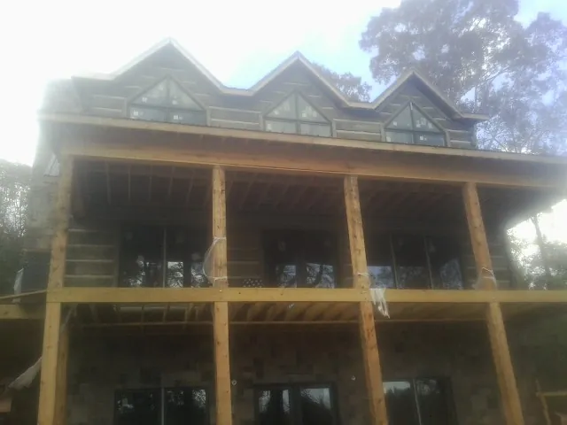 Dormers and porch framing on a large log home under construction — Roof Coating work by our crew in Lakeside